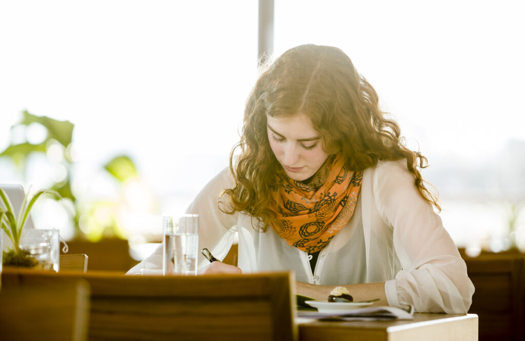 Young woman with note-book writing in cafe